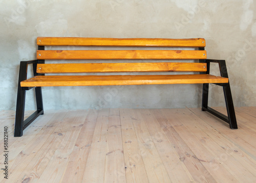 natural light. a bench made of metal and painted black. the wood is covered with yellow varnish and impregnation and slightly aged.
