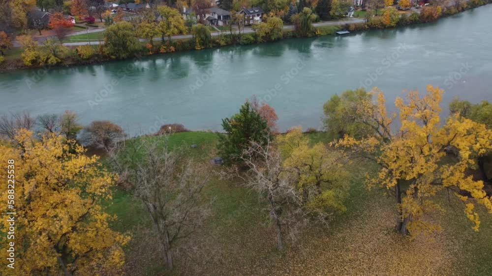 Swooping aerial over vibrant fall trees crosses river, enters suburb neighborhood Swooping aerial over vibrant fall trees crosses river, enters suburb neighborhood