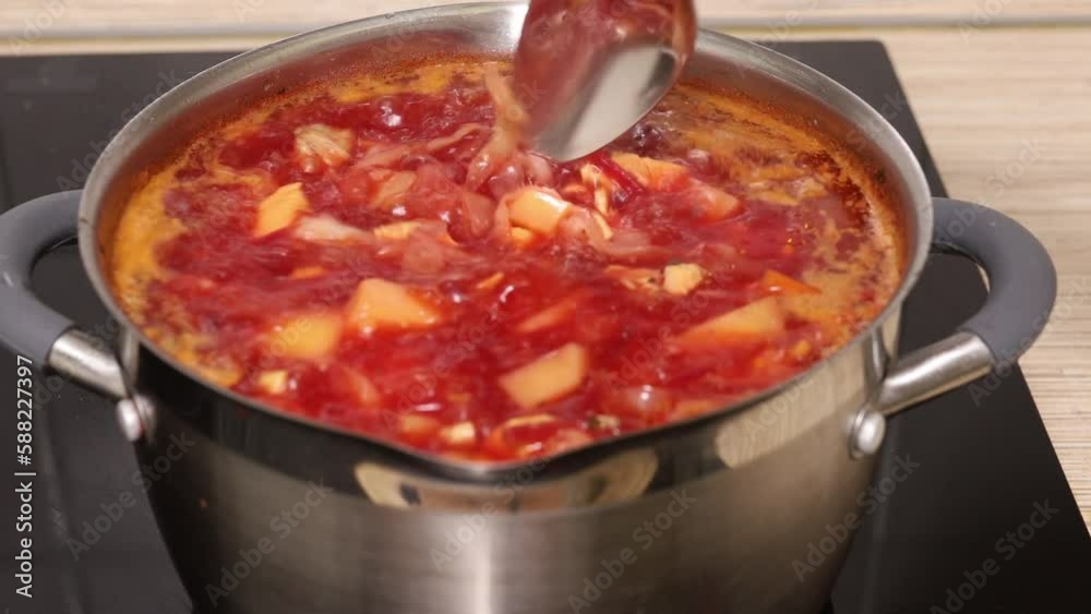 Close up stationary video of boiling tasty and juicy red beet soup borshch in saucepan on induction oven panel. Cooking food recipe and traditional Ukrainian, Russian dish culinary, cuisine. Video