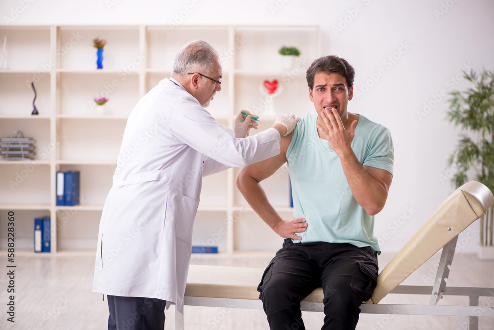 Fototapeta premium Young male patient visiting old male doctor in vaccination conce