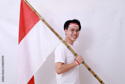 Asian man celebrate Indonesia Independence Day on 17 August by holding Indonesian flag. Isolated photo