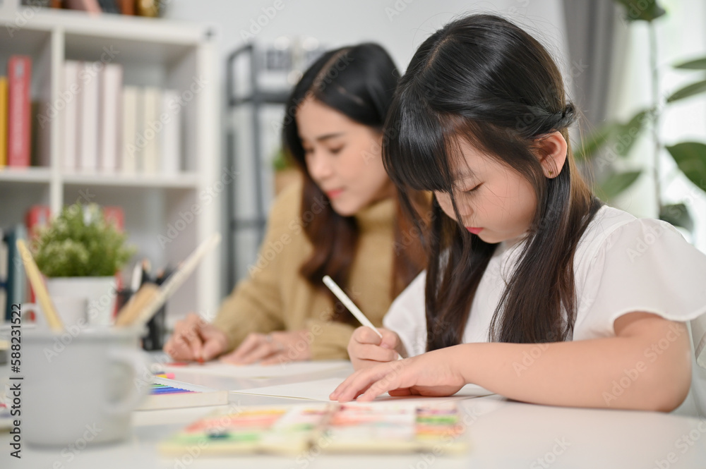 Cute young Asian girl drawing cute animals on paper, spending creativity time with her mother