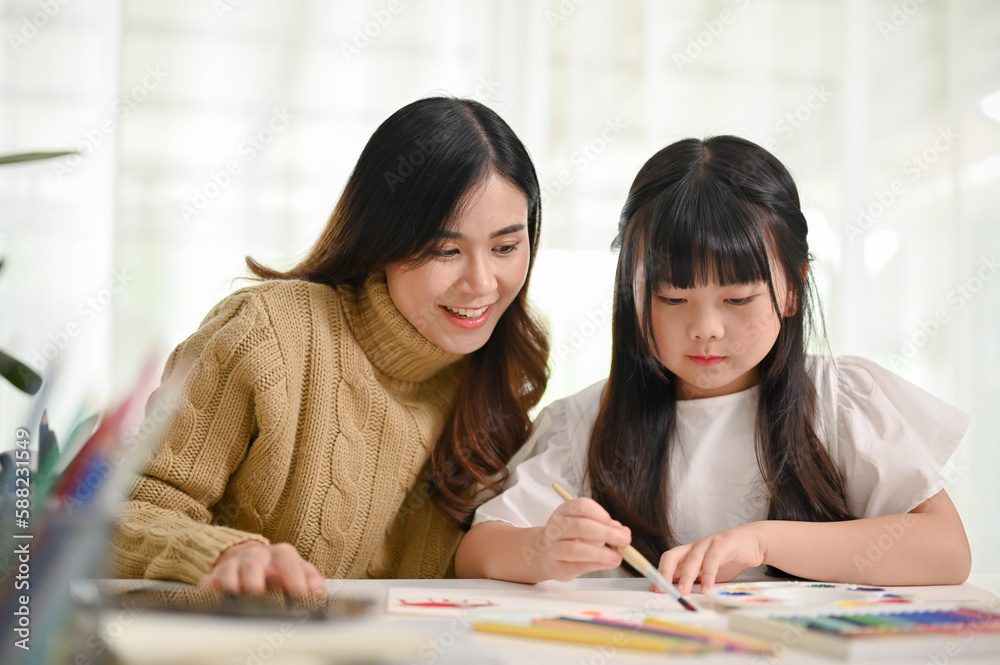 Kind Asian mom teaching her little daughter to paint and coloring with water color Kind Asian mom teaching her little daughter to paint and coloring with water color