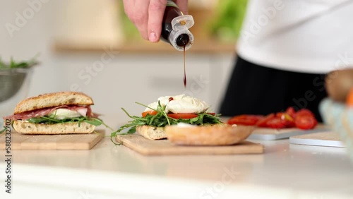 Process of pouring balsamic vinegar on sandwich. Baguette arugula and mozzarella. Fresh Italian home made food concept
