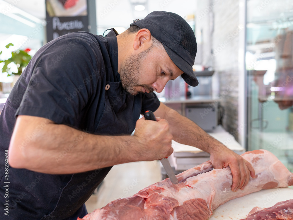 butcher man cutting a large piece of meat with force