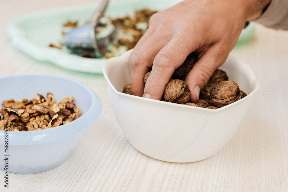 Closeup photo of man taking walnuts from bowl for cracking Closeup photo of man taking walnuts from bowl for cracking