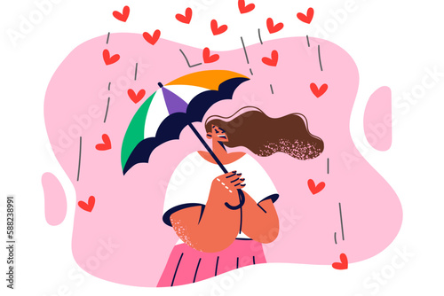Positive woman tries umbrella to hide from falling hearts symbolizing excessive love and care
