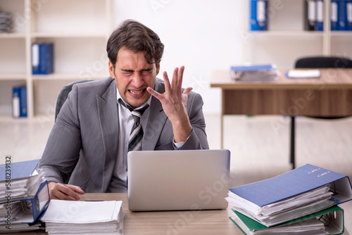 Young male employee unhappy with excessive work in the office