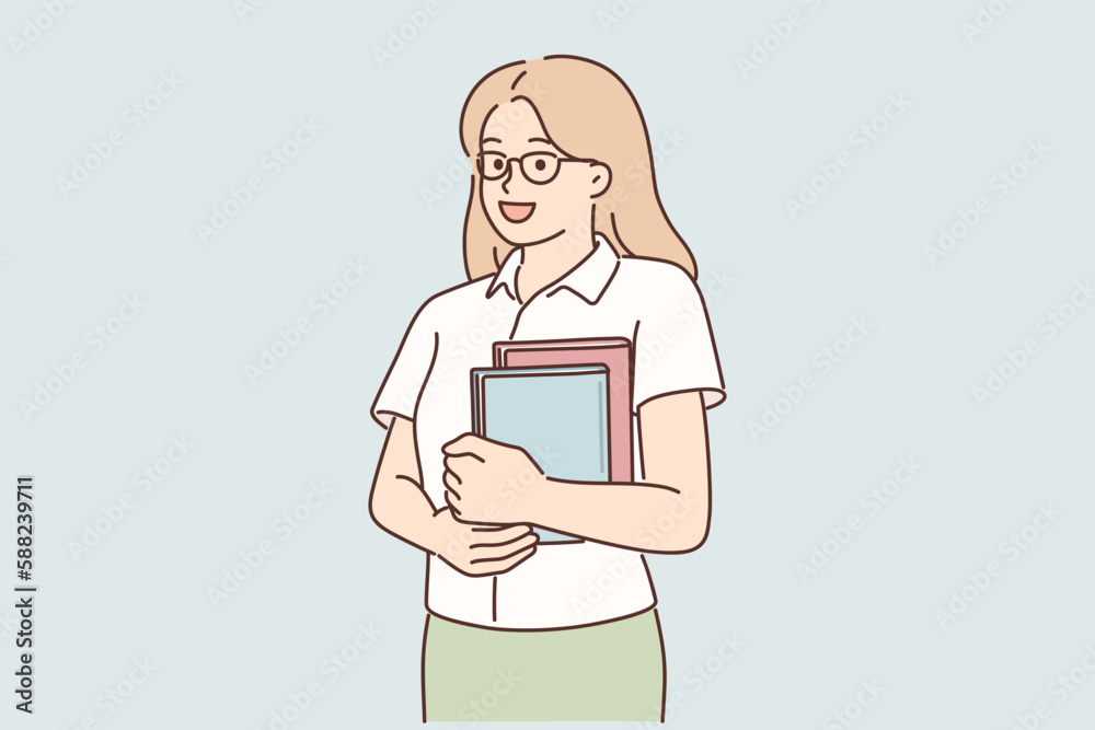 Young girl student stands with books in hands posing with glasses and looking at screen Young girl student stands with books in hands posing with glasses and looking at screen