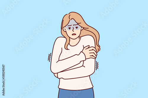 Freezing woman hugging shoulders trying to keep warm and feeling chills after contracting flu infection or fever. Freezing girl in sweater dreams of warm house to wait out cold weather 