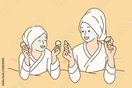 Two girls with hygienic mask on face rest lying on bed during rejuvenating spa treatment