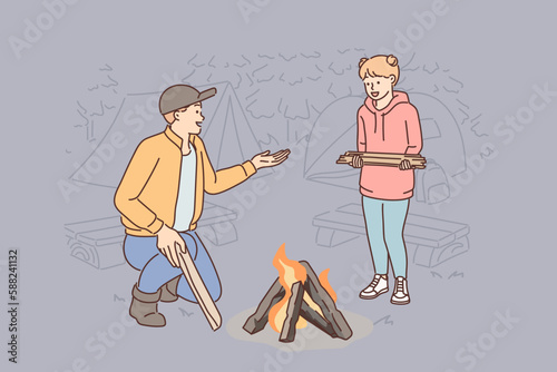 Father and daughter make fire together during family camping trip and enjoy trip to nature together