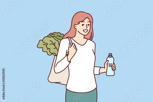 Woman with reusable eco shopping bag and recycled plastic bottle returns from farmer vegetable market. Girl takes care of environment by refusing to use plastic packaging that pollutes nature 