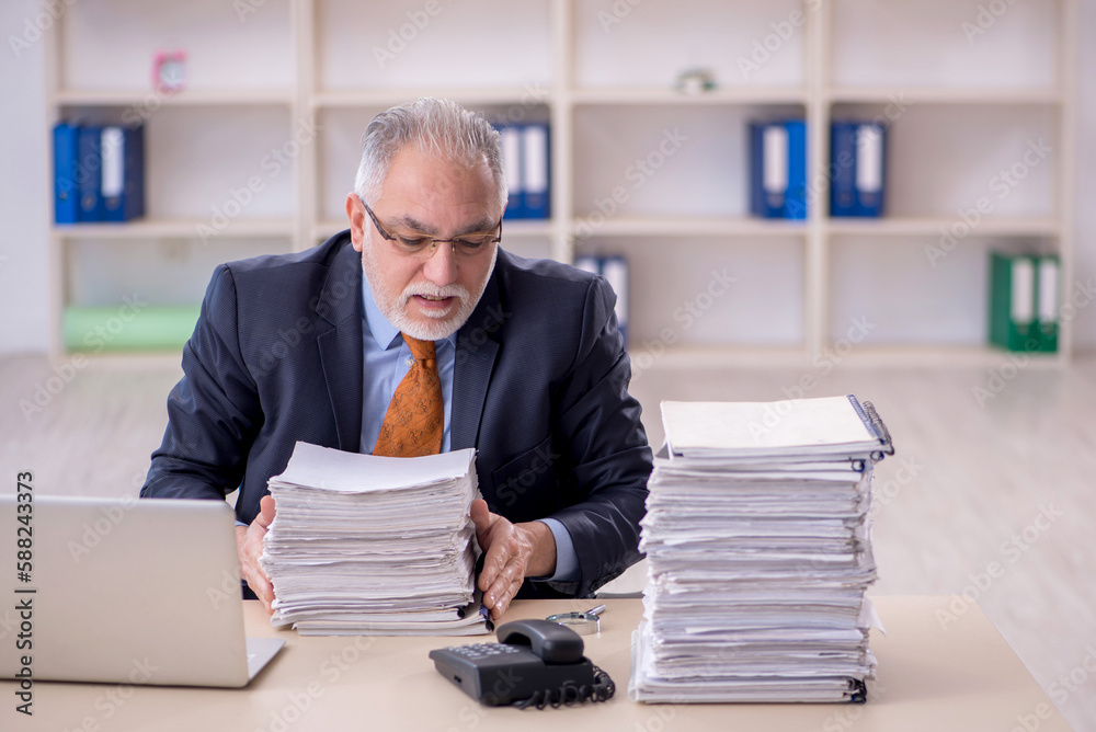Old male employee unhappy with excessive work in the office Old male employee unhappy with excessive work in the office