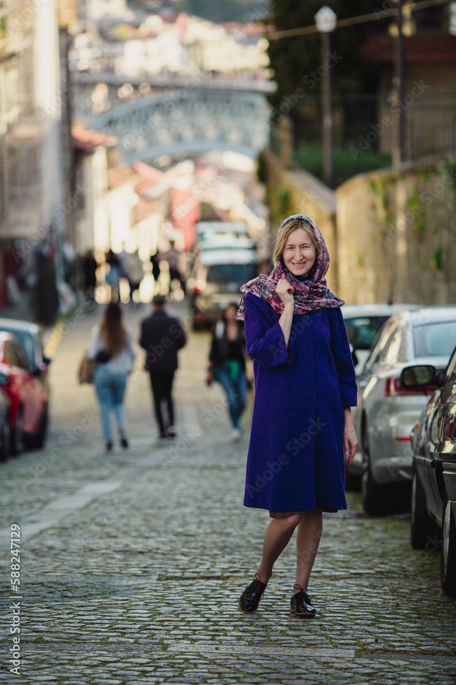 A woman poses on the street in Porto, Portugal.