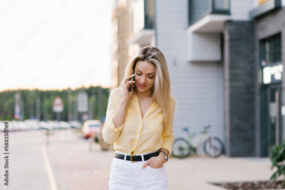Happy young woman smiling and walking in the street talking on a smartphone