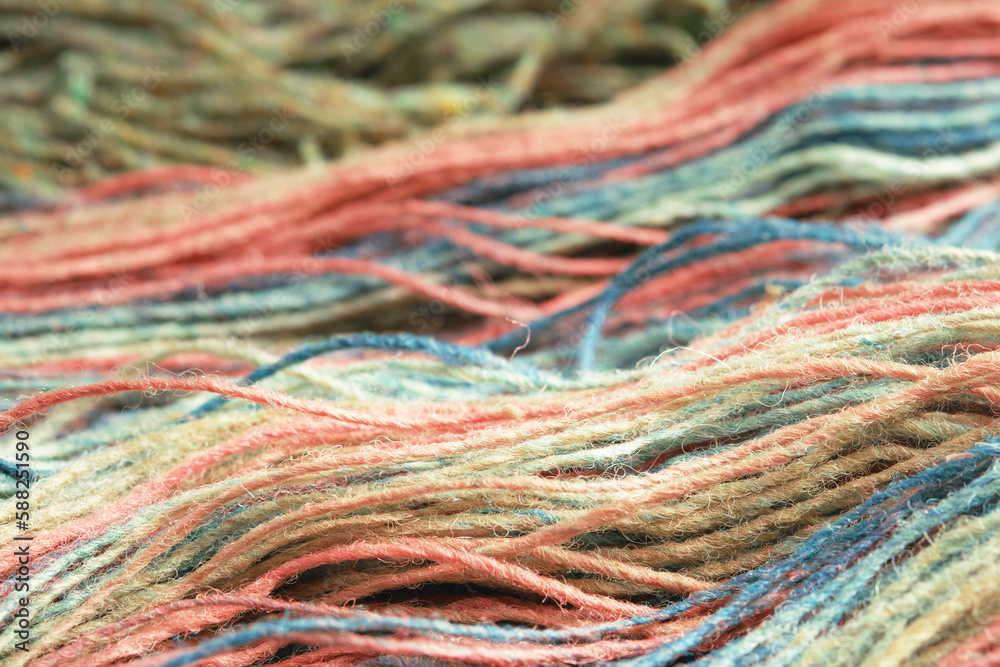 Threads from natural organic sheep wool. Close-up, macro. Two unwound skeins of green and rainbow knitting yarn.
