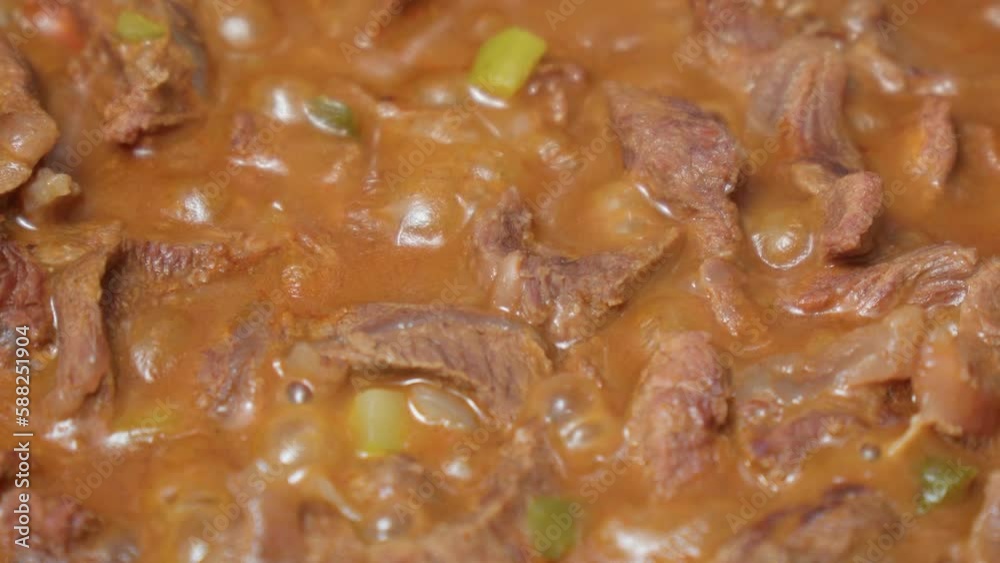 Cooking pieces of stewed beef with pickled cucumbers close-up. Cooking pieces of stewed beef with pickled cucumbers close-up.