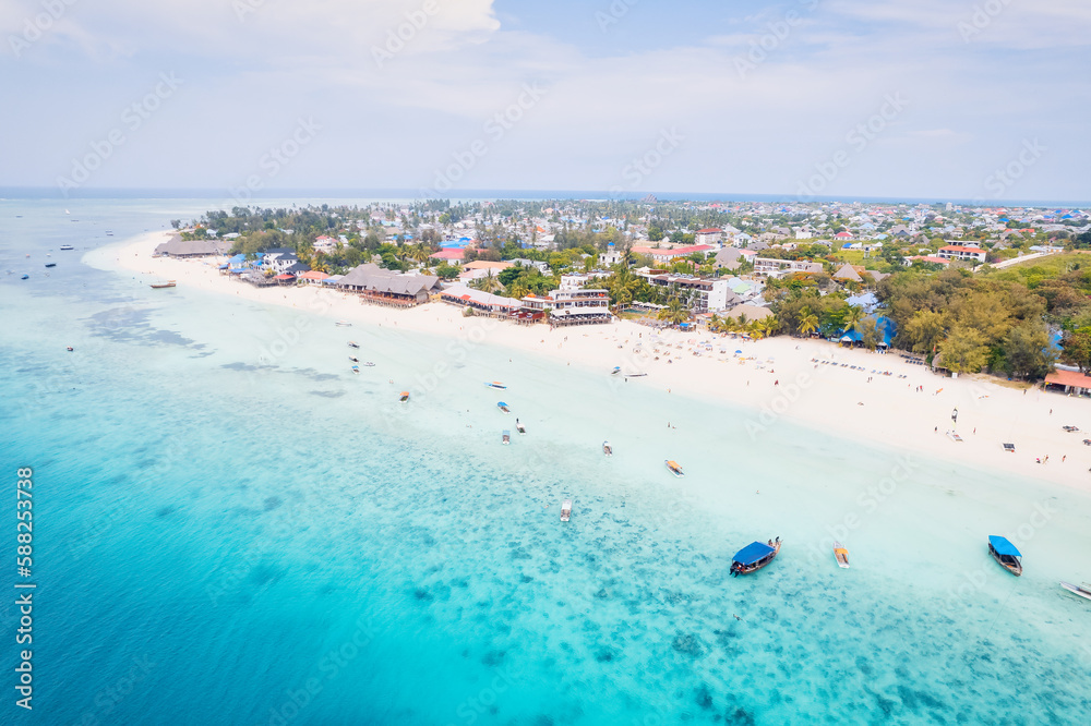 The aerial view of Zanzibar's beaches captures the essence of a tropical paradise with palm trees, umbrellas, white sand, and the sparkling blue waters of the Indian Ocean.