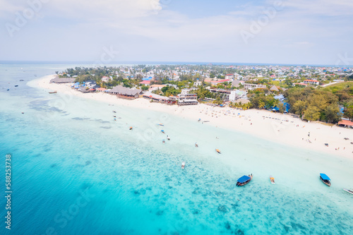 The aerial view of Zanzibar's beaches captures the essence of a tropical paradise with palm trees, umbrellas, white sand, and the sparkling blue waters of the Indian Ocean.