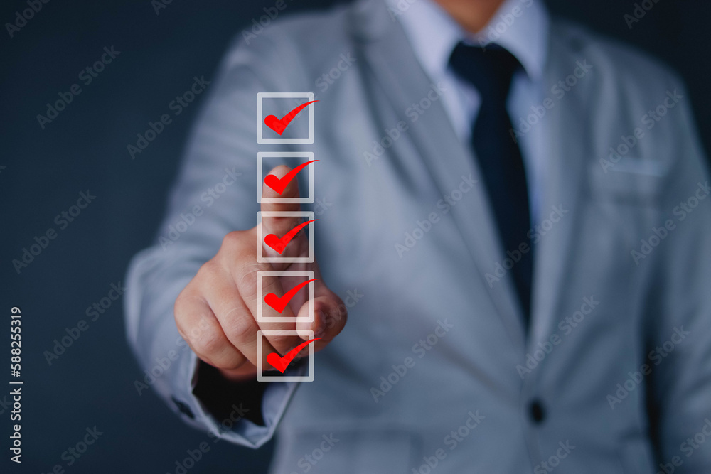 Businessman checks a check mark on the checklist with a check mark
