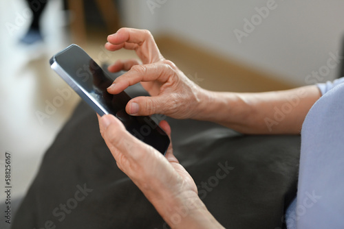 Close up view of senior woman hand holding smart phone, browsing wireless internet or chatting online