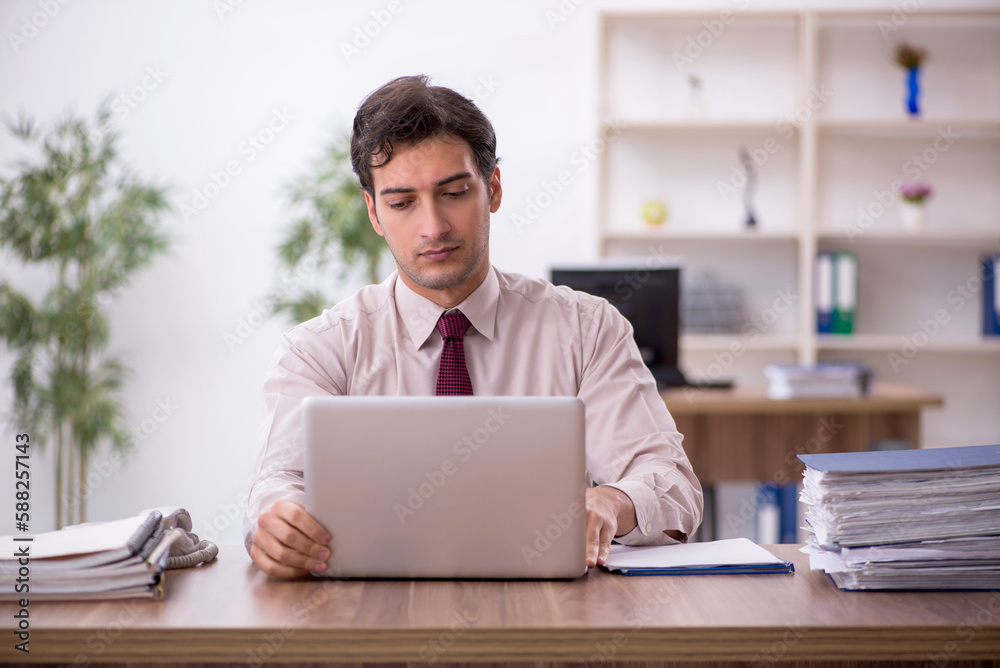 Young male employee and too much work in the office Young male employee and too much work in the office