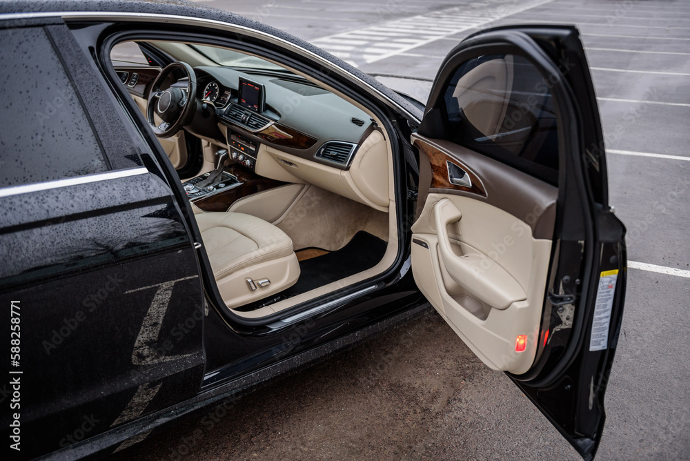 Side view of the open passenger door, mirror, dashboard of car. Right front door. A new modern shiny parked black car. Interior luxury car with tinted glass standing at parking. Modern car exterior.