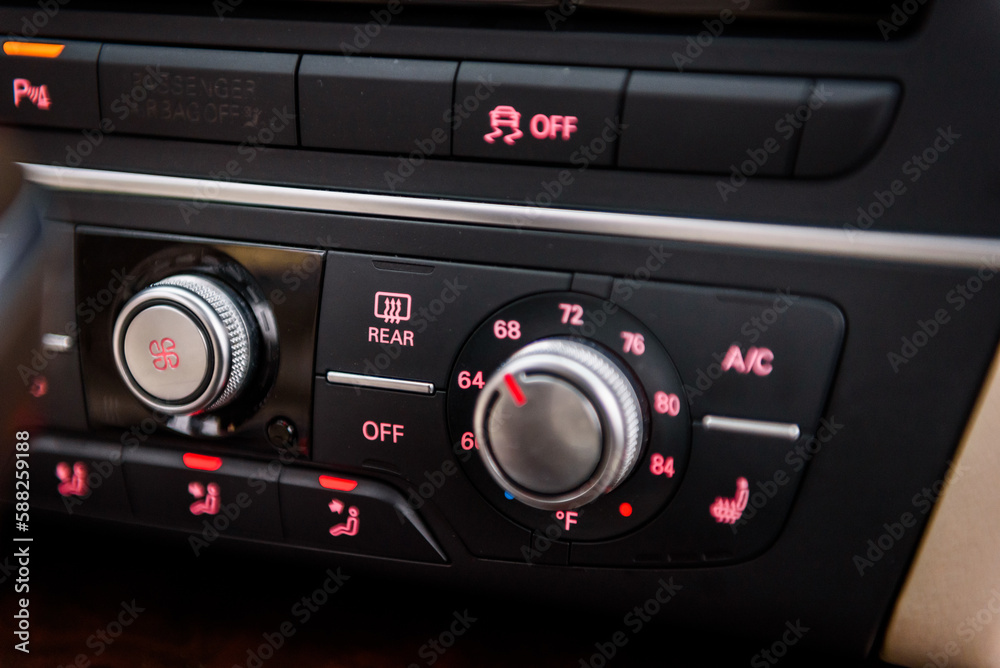 Climate control AC unit in the new car is highlighted in the dark. Air conditioning button inside a car. Modern car interior details. Details closeup. Climate control AC unit in the new car is highlighted in the dark. Air conditioning button inside a car. Modern car interior details. Details closeup.