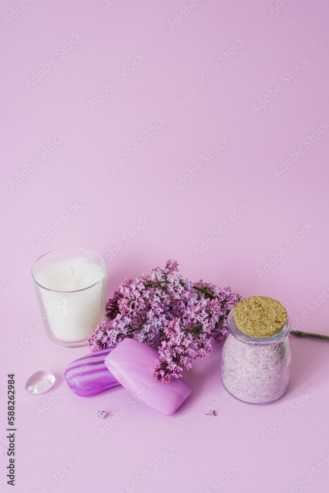 Spa setting with lilac flowers. Sea salt in a glass jar, soap and candle on the background Spa setting with lilac flowers. Sea salt in a glass jar, soap and candle on the background