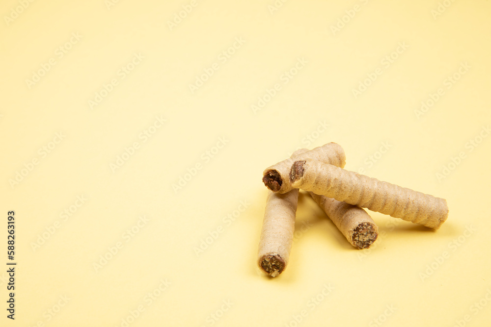 wafer rolls with chocolate isolated on light yellow background