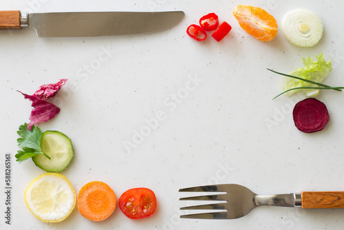 Frame of sliced vegetables and fruits with knife and fork on light background, healthy diet concept