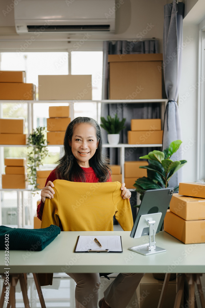 Fashion blogger concept, Senior Asian women selling clothes on video streaming.Startup small business SME, using smartphone or tablet taking receive and checking Fashion blogger concept, Senior Asian women selling clothes on video streaming.Startup small business SME, using smartphone or tablet taking receive and checking