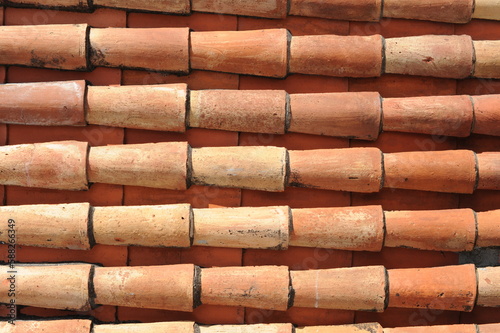 Red and orange roof tiles texture pattern on roof of an old historical building