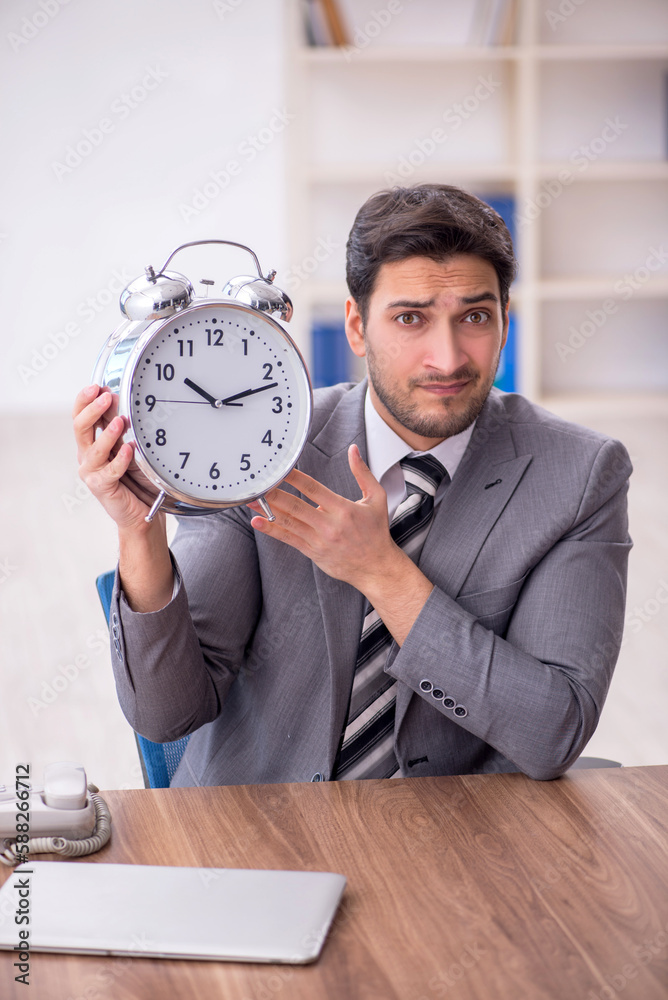 Young male employee in time management concept Young male employee in time management concept