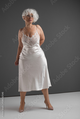 Full-length portrait of older woman in glasses and silk negligee