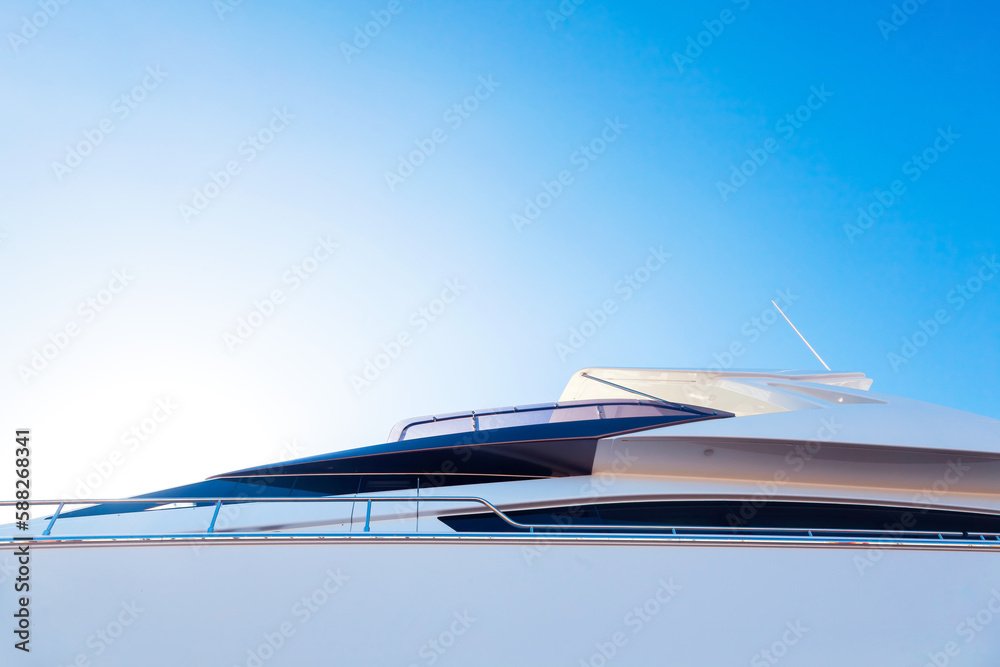 The hull of a luxury, motor, white yacht, with portholes on it, against the blue sky and the light of the sun in the corner, bottom view.