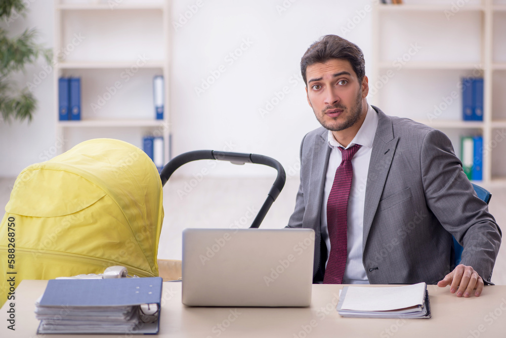 Young male employee looking after newborn at workplace Young male employee looking after newborn at workplace