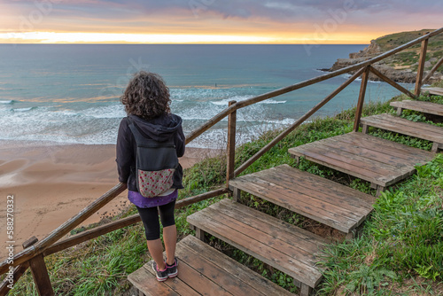 Woman on the stairs of a cliff watching the sunset