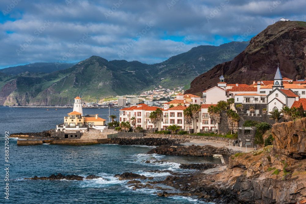 Marina da Quinta Grande, Madeira, Portugal. Seaside small village with lighthouse on rocky cliffs.