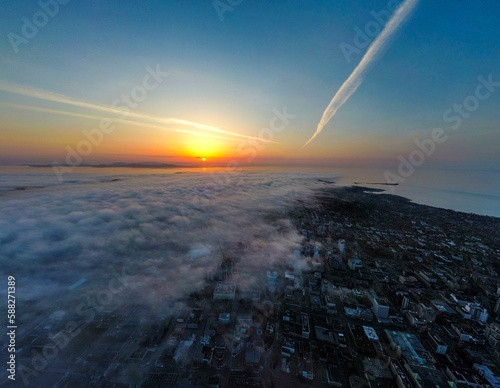 Aerial cityscape view with high buildings covered with fog against a scenic sunset