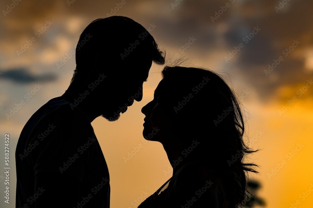 Silhouette of a young couple looking at each other against a sunset background