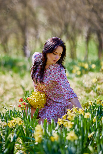 A beautiful woman in a garden with yellow snowdrops on a spring day.