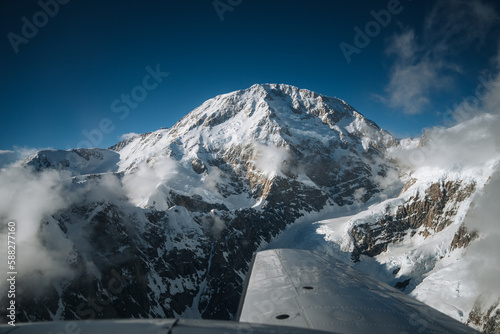 Aerial View of the Great Mount Denali known as McKinley Peak in the Alaskan Wilderness, Denali National Park, AK. Sun and blue sky, Snow and clouds forming blowing off the peak. A Beautiful Snowscape photo