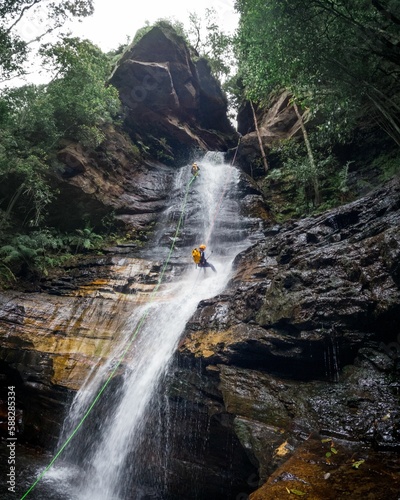 Few adventurers abseiling a waterfall cliff