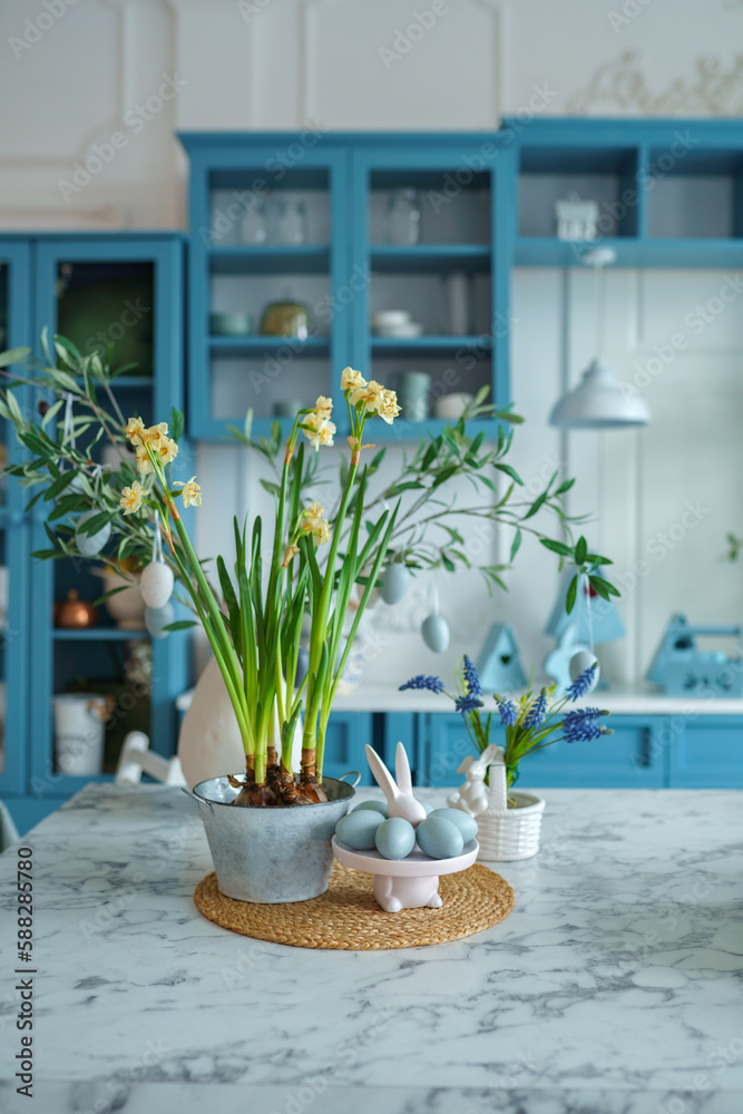 Blue kitchen interior with furniture. Stylish cuisine with flowers in vase. Wooden kitchen in spring decor. Cozy home decor. Kitchen utensils, dishes and plate on table. kitchen island in dining room,