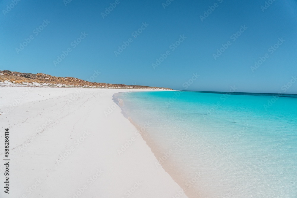 Scenic view of a sandy beach being washed by blue sea on a sunny day