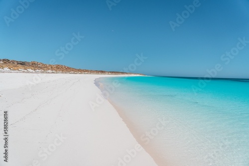 Scenic view of a sandy beach being washed by blue sea on a sunny day