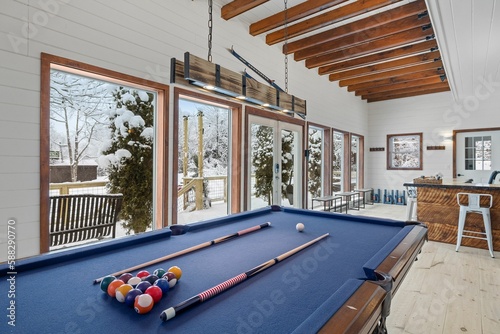 Large pool table in a room next to a large window