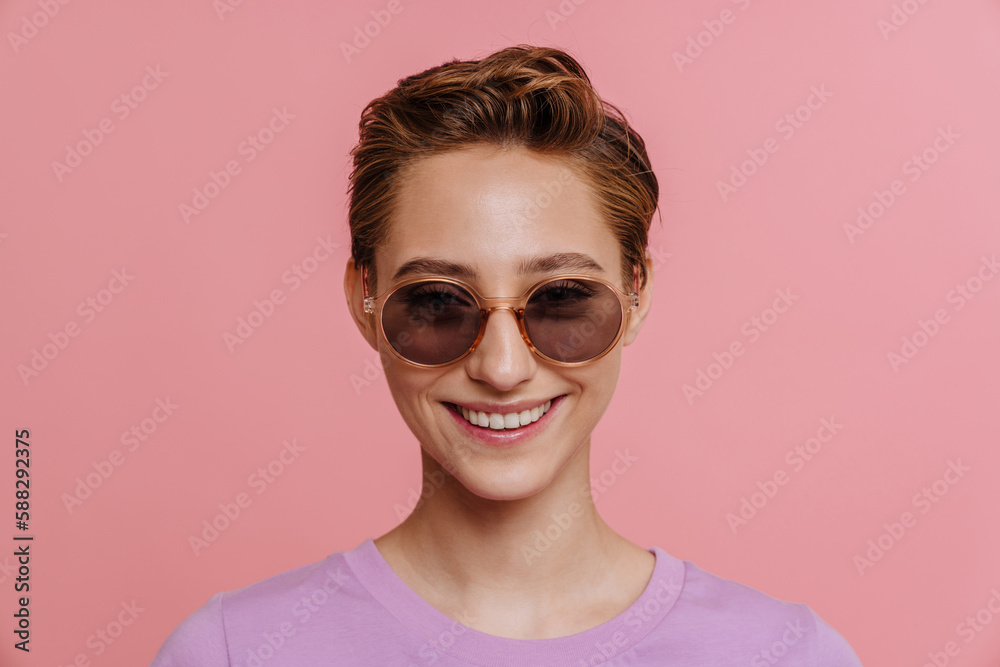 Young beautiful smiling woman in sun glasses looking at camera